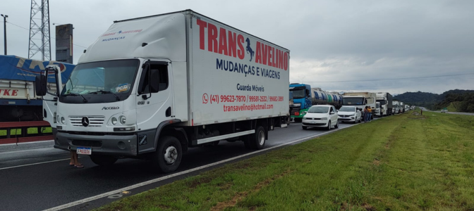 Caminhão da TransAvelino realizando mudança de casa em rodovia, representando transporte seguro e profissional