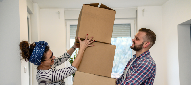 Casal carregando caixas de mudança, ilustrando os cuidados necessários para evitar danos durante o transporte