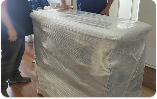 Móvel embalado com plástico stretch e proteção adequada durante serviço de mudança residencial.